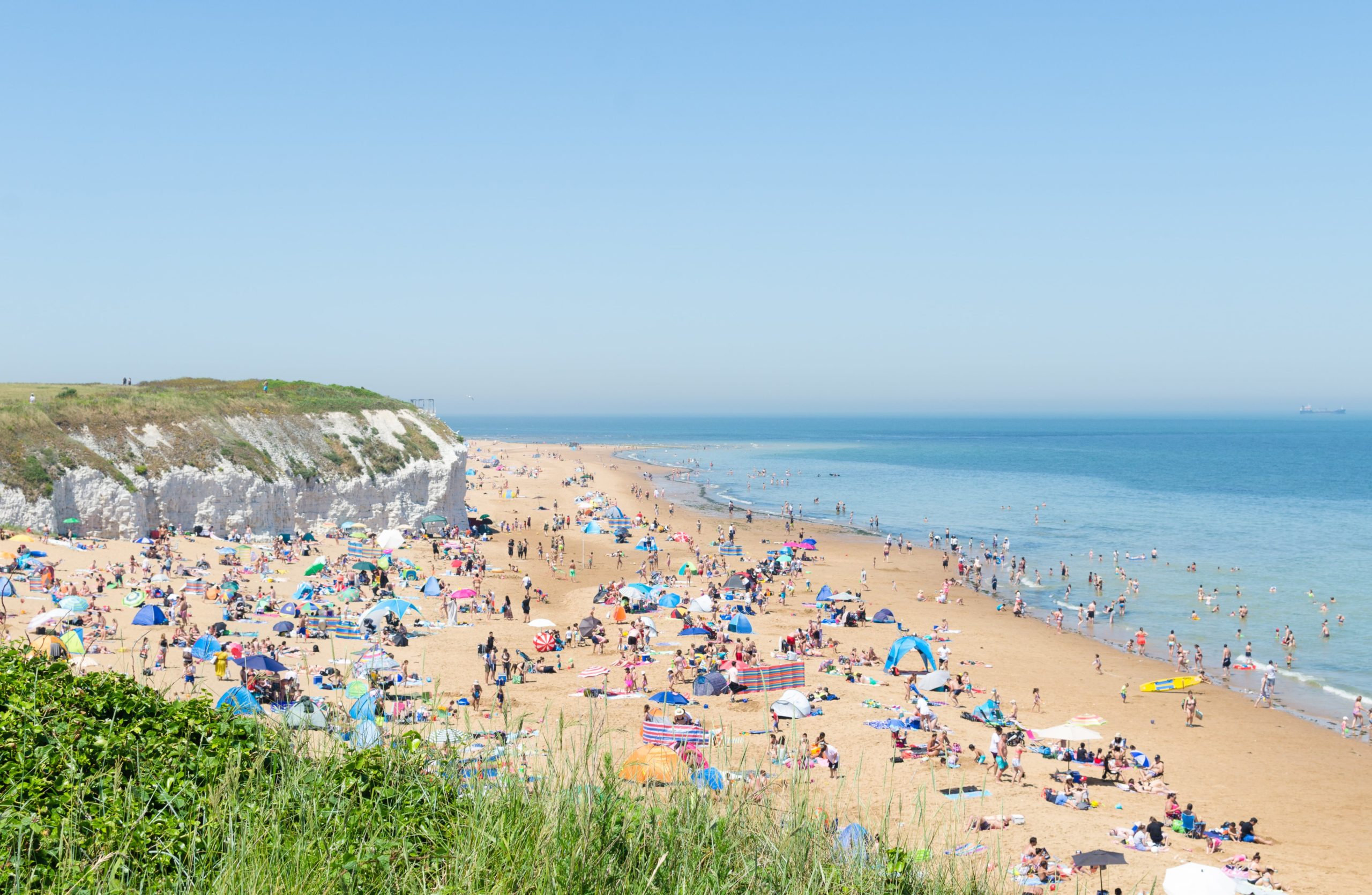 Golden sandy beach with striking white chalk cliffs and clear blue sea