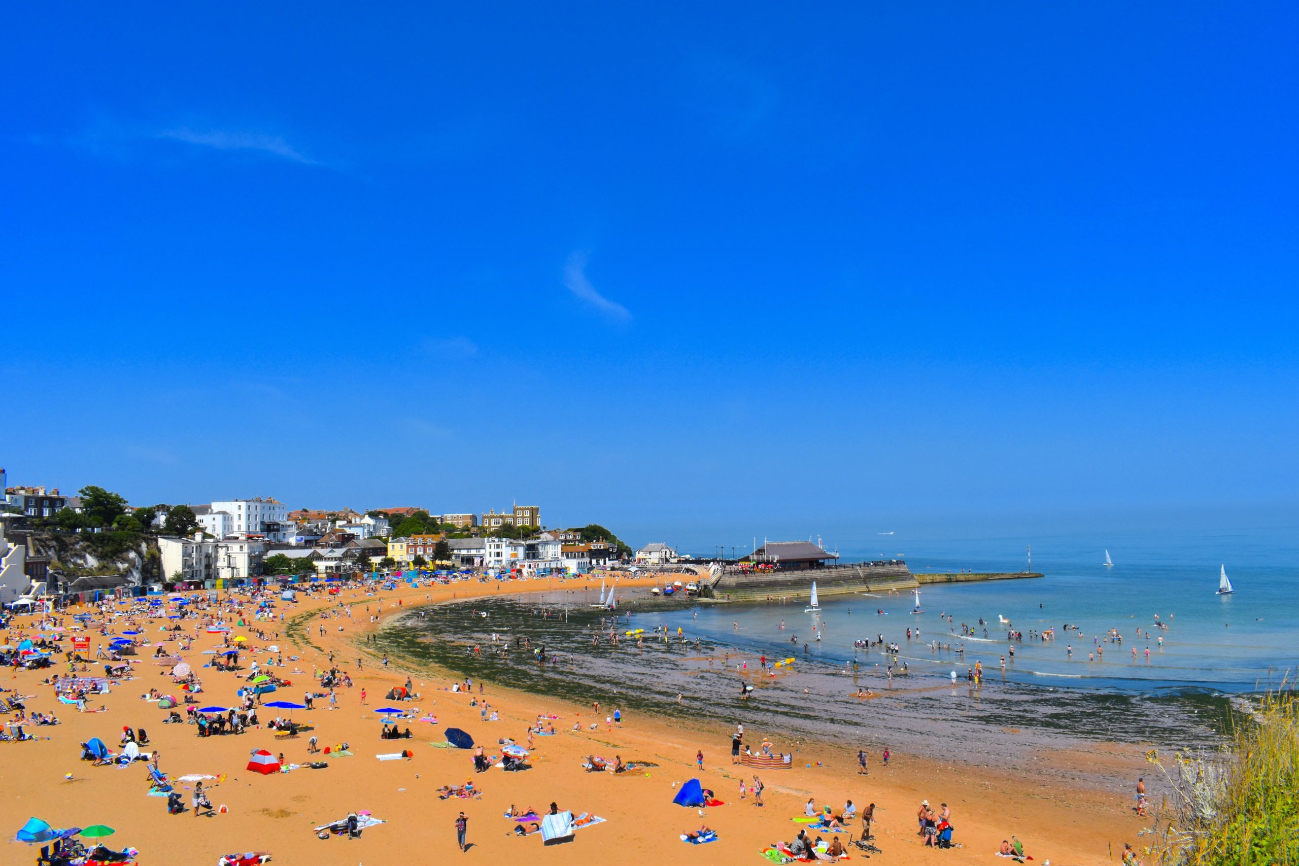 Sandy beach with low tide, golden sand, and families enjoying the sun