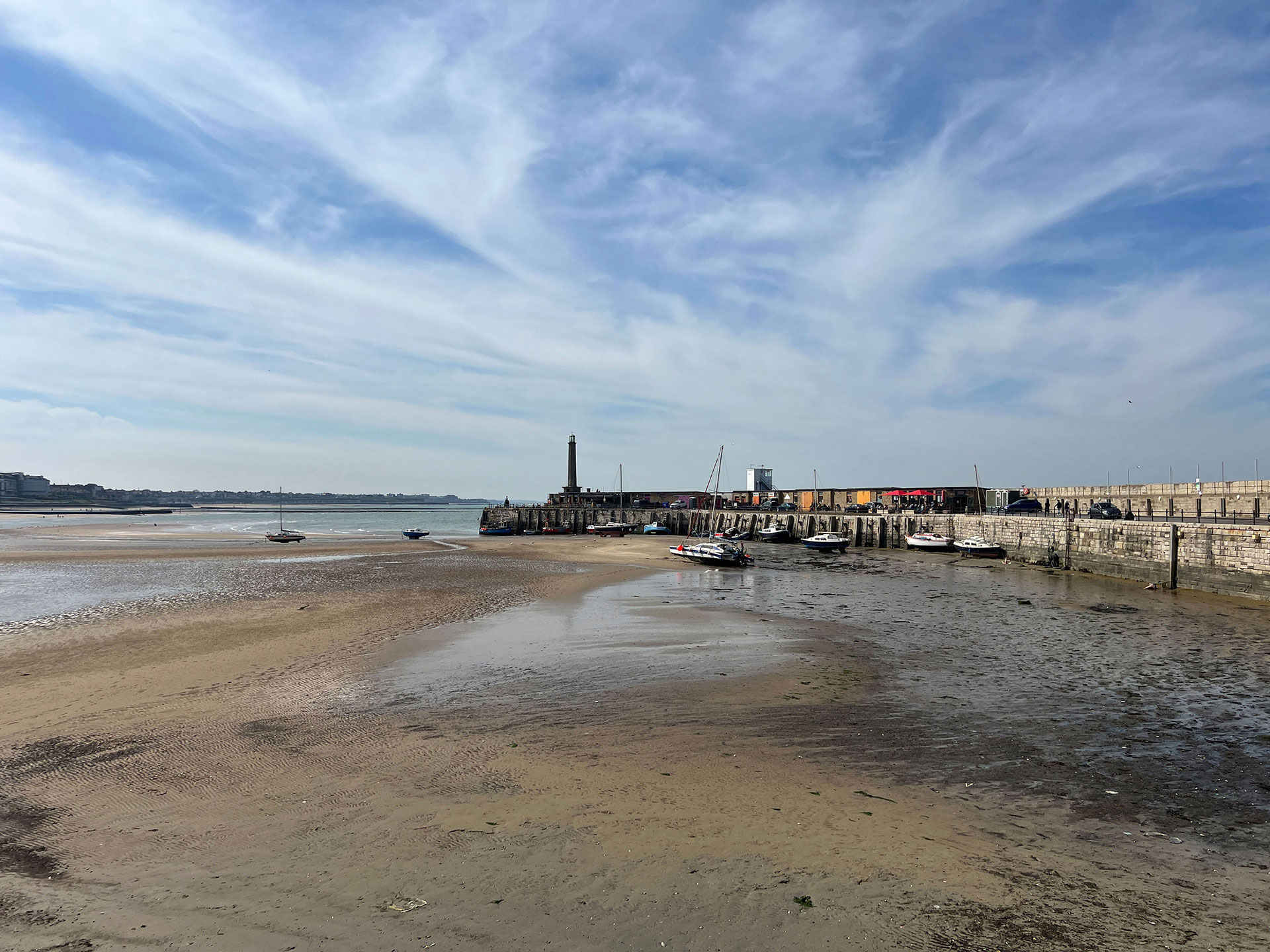 Margate Harbour Arm with boats on the sand at low tide