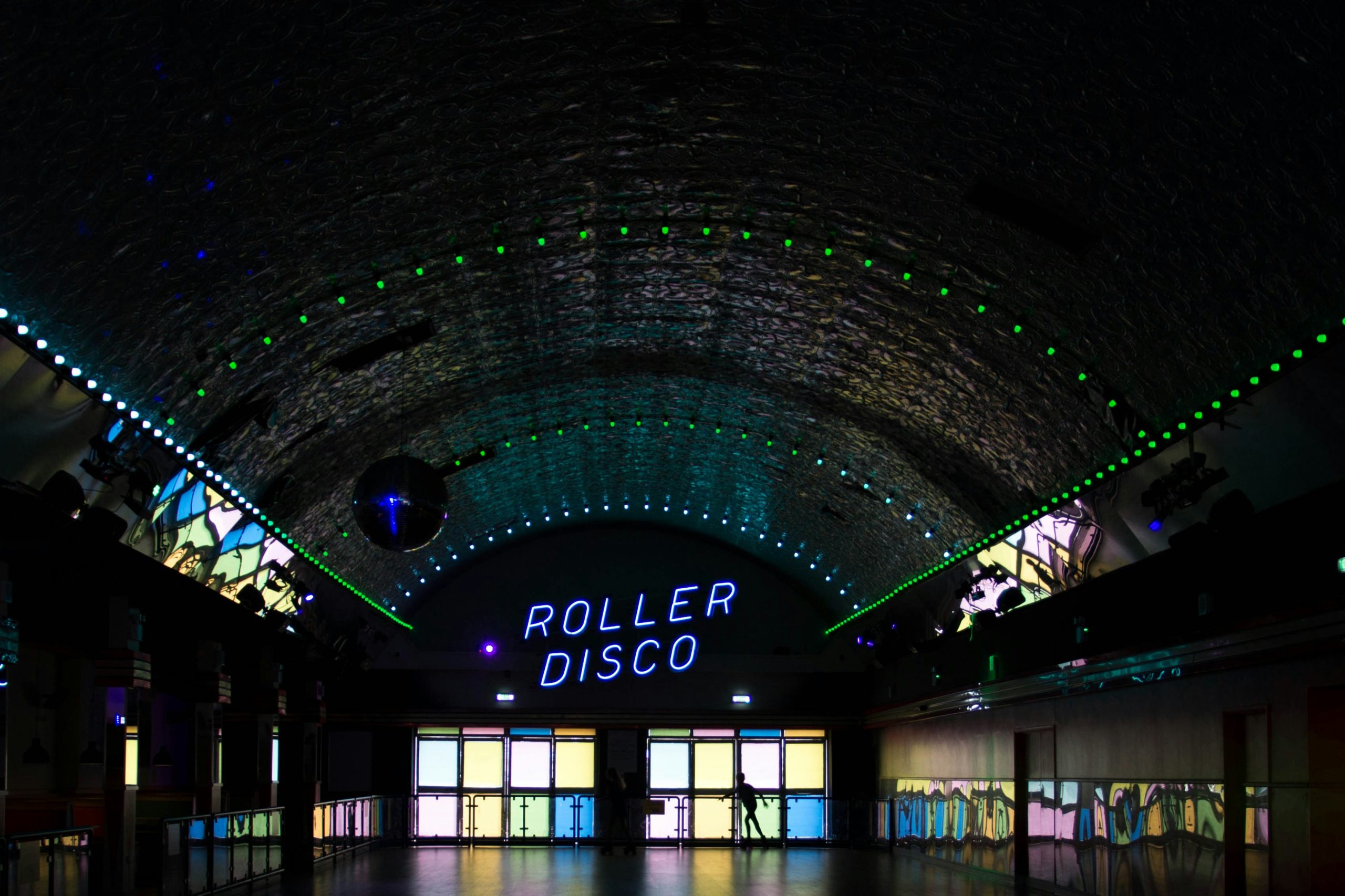 Dreamland Margate’s roller disco lit up with neon lights and a mirror ball under an arched ceiling.