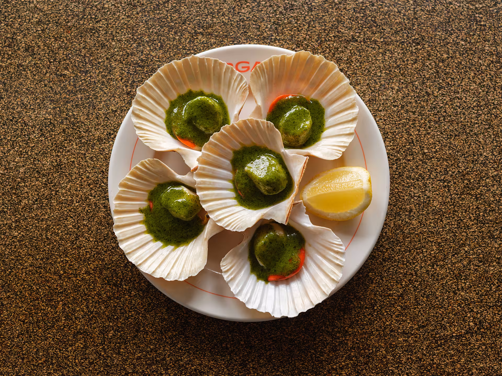 Freshly grilled scallops with vibrant green herb butter served in their shells, a signature dish at Sargasso Bar.