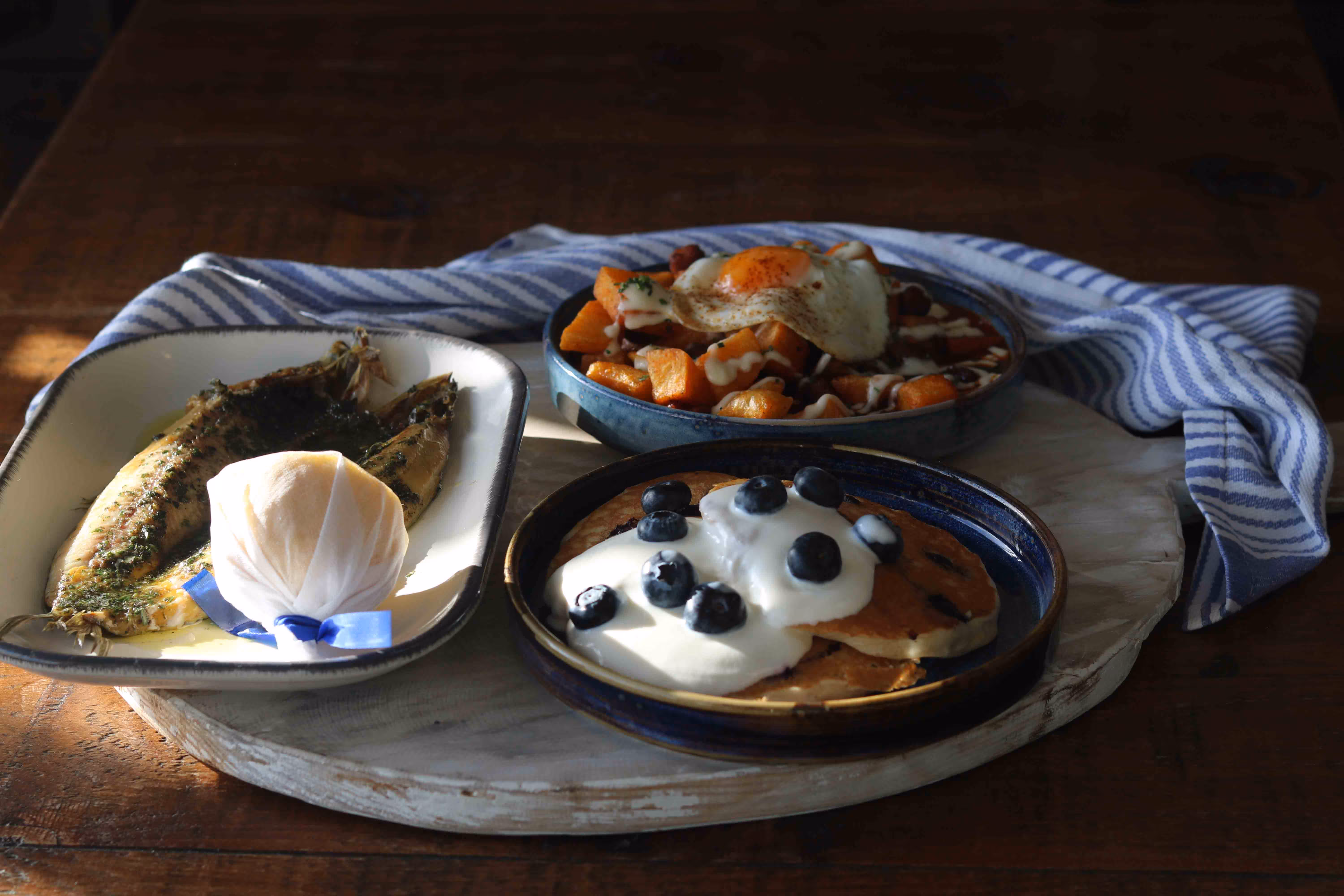 A selection of breakfast dishes at Kebbells in Broadstairs, including Grilled Kippers with Seaweed Butter, Buttermilk Pancakes with Blueberries, and a Char-grilled Smoked Bacon Chop with Fried Egg.