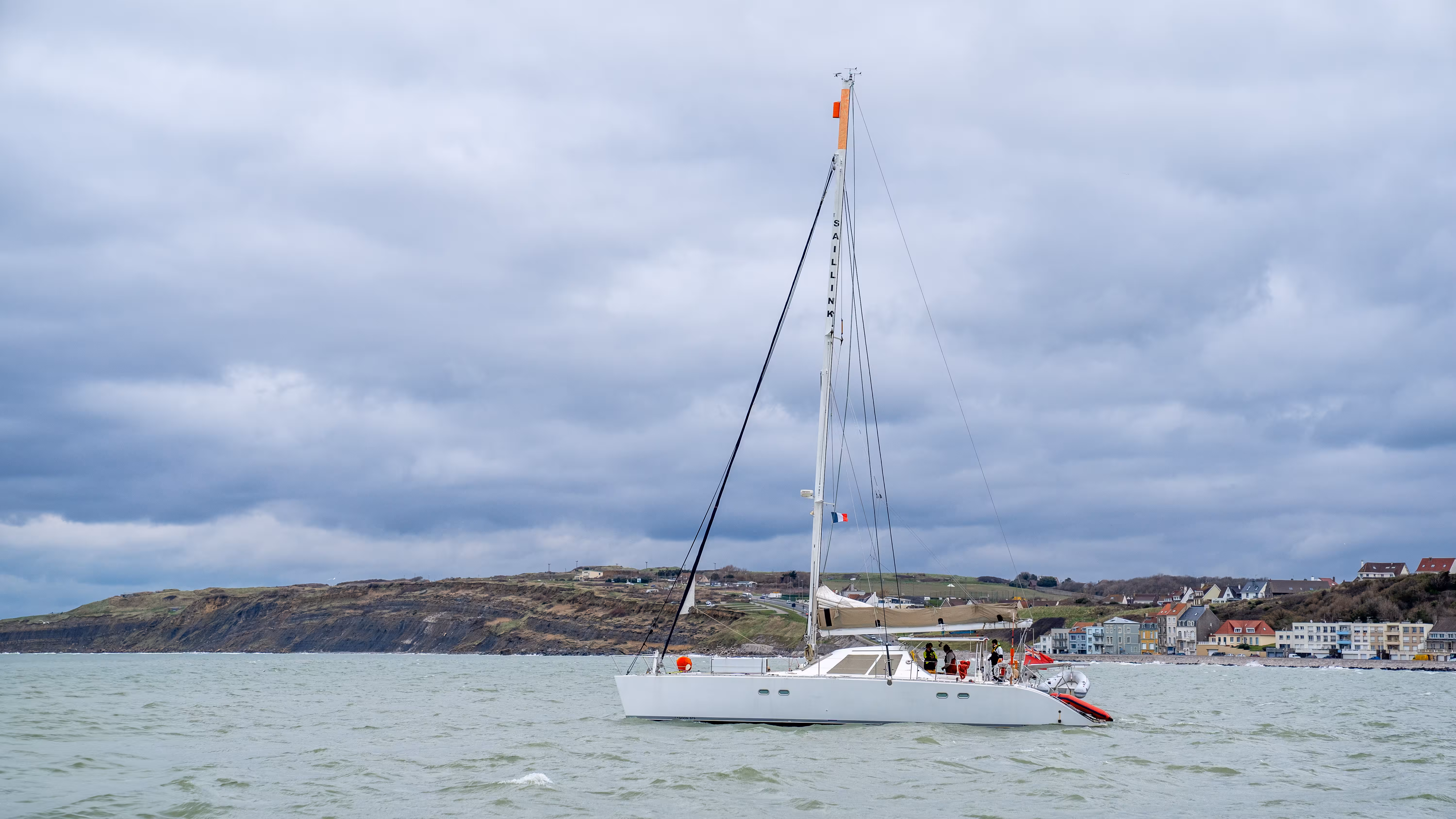 SailLink catamaran ferry approaching the French coast on a cloudy day.