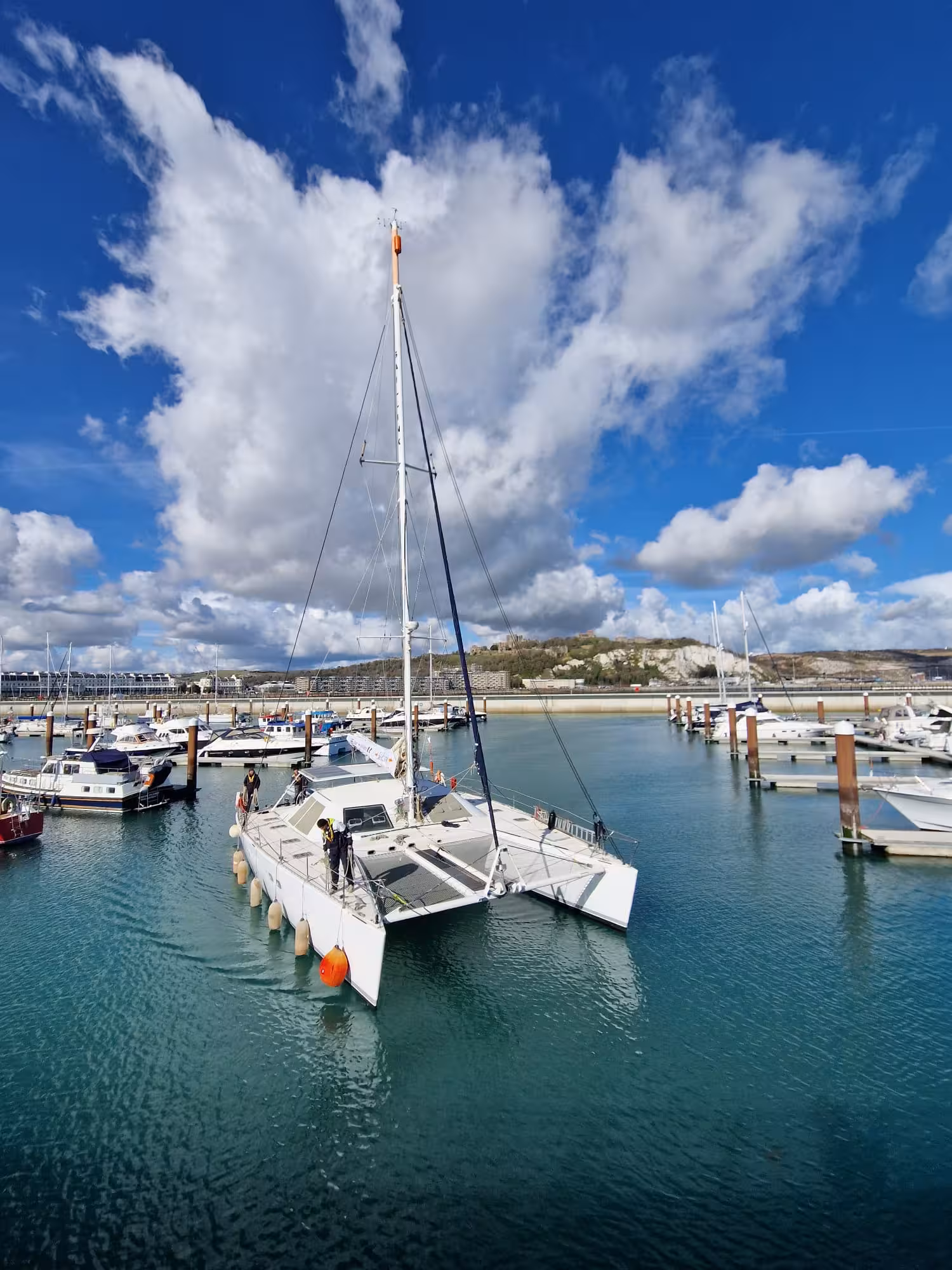 SailLink’s white catamaran ferry in the marina at Dover on a sunny day with puffy clouds above.