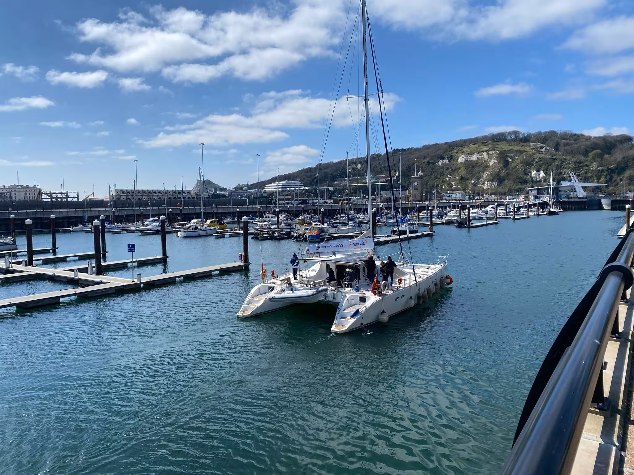 A SailLink catamaran ferry in a busy marina at Dover Harbour.