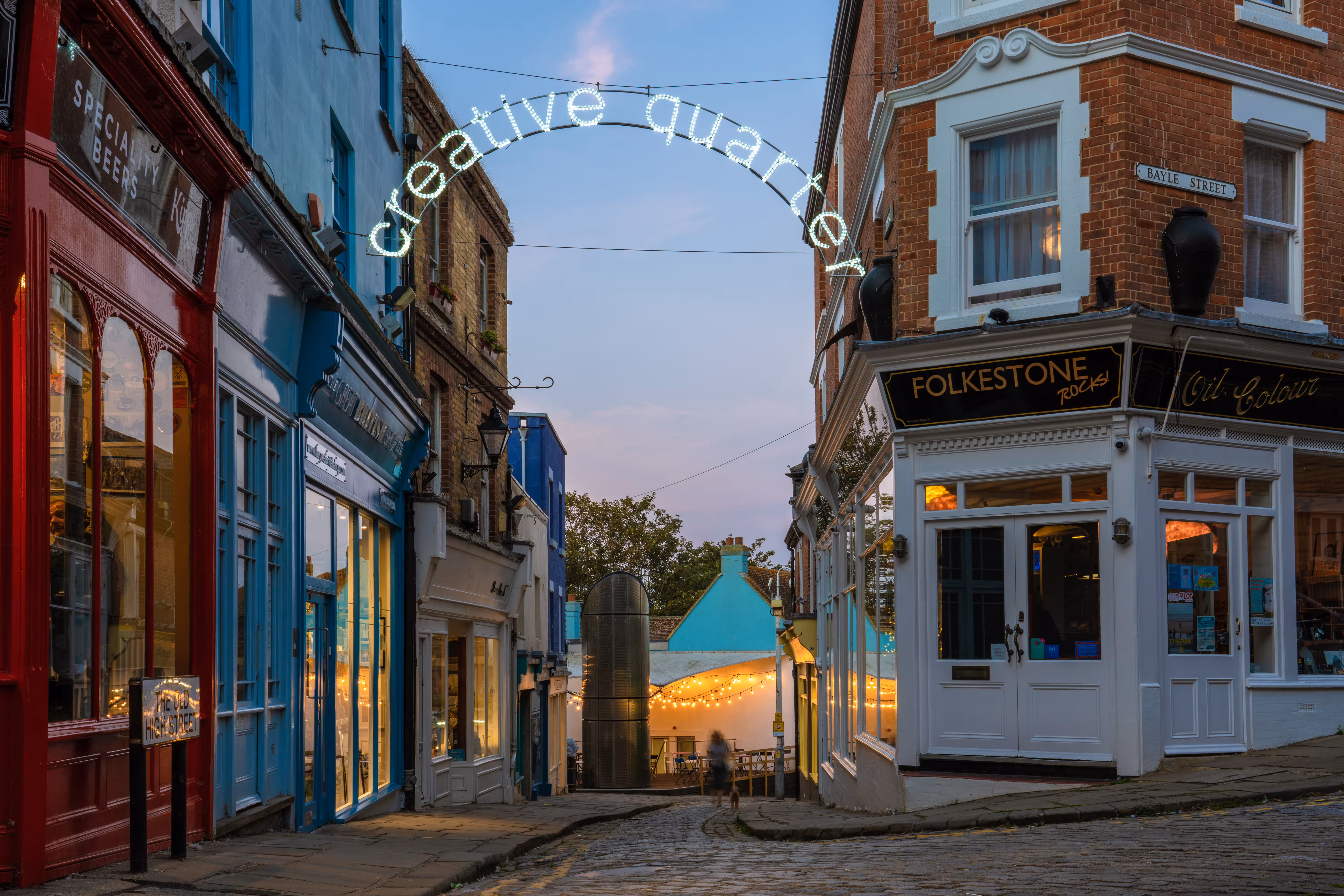 Folkestone Creative Quarter at dusk with colourful shopfronts and cobbled streets leading towards the seafront.