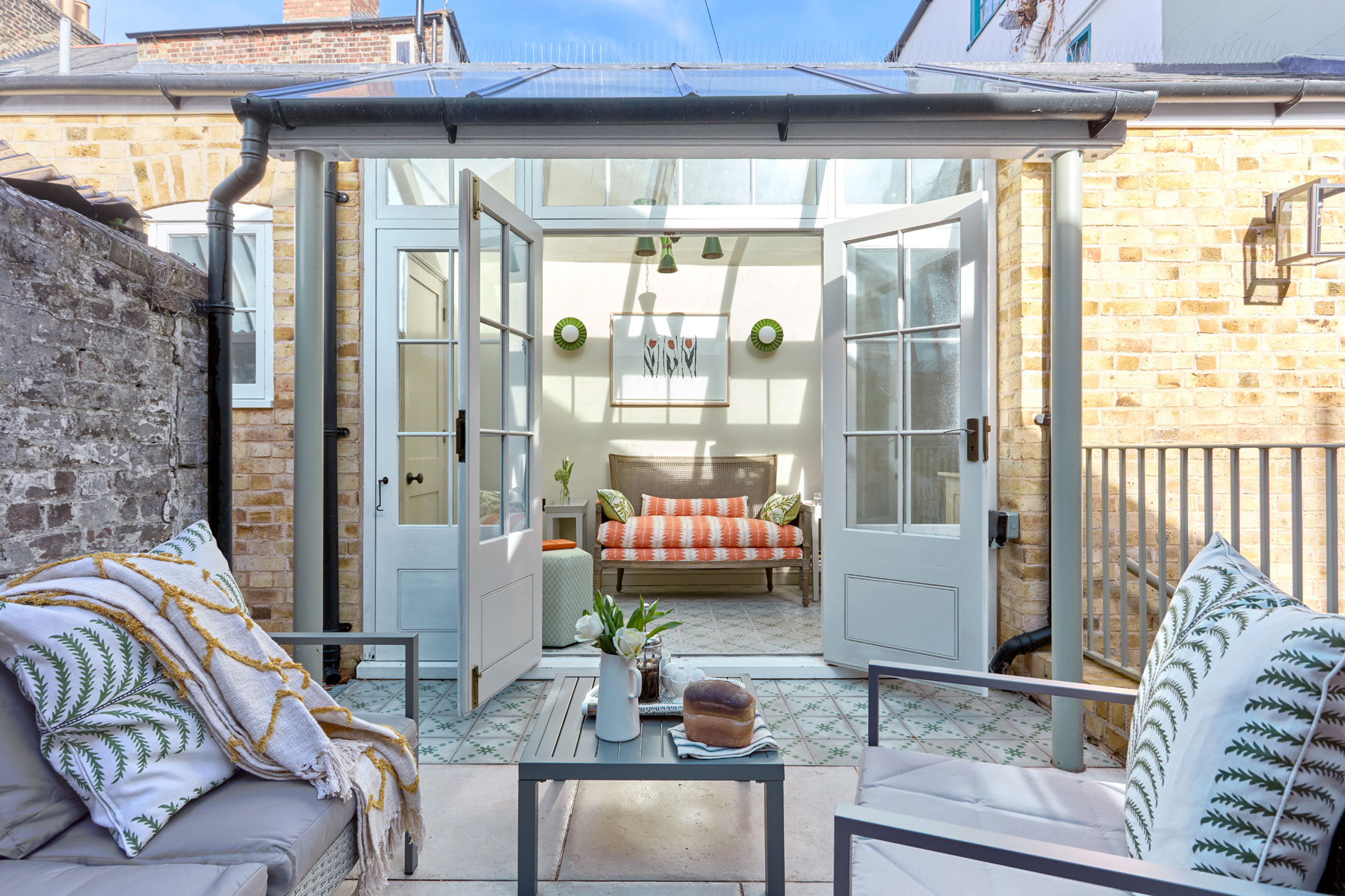 Private courtyard garden at Sailmaker’s House, a holiday cottage in Deal, Kent, with outdoor seating, French doors and a light-filled garden room.
